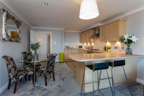 a kitchen with a counter and a table and chairs at Harris Retreat - Donnini Apartments in Ayr