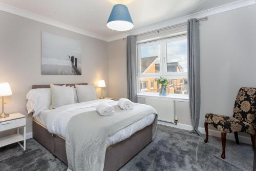 a bedroom with a bed and a window and a chair at Harris Retreat - Donnini Apartments in Ayr