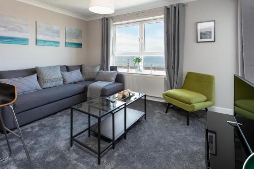 a living room with a couch and a table and chairs at Harris Retreat - Donnini Apartments in Ayr