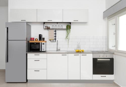 a white kitchen with white cabinets and appliances at Mr. Ben Yehuda - By TLV2GO in Tel Aviv