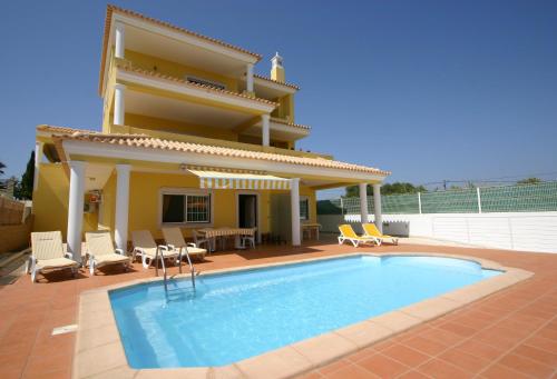 a villa with a swimming pool in front of a house at Villa vista mar e piscina in Fuzeta