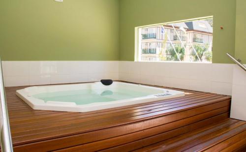 a large bath tub in a room with a window at Apartamento - Itaipava in Itaipava