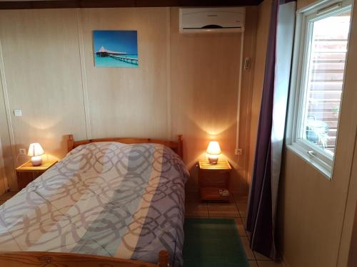 sypialnia z łóżkiem, oknem i 2 lampami w obiekcie Maison à Saint-Leu, vue panoramique sur l'océan à 2 minutes des plages w mieście Saint-Leu