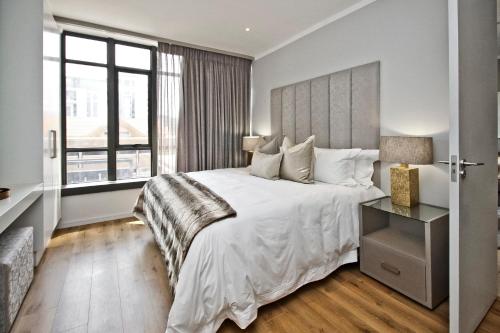 um quarto com uma grande cama branca e uma janela em SANDTON APARTMENT 15 WEST ROAD SOUTH em Joanesburgo