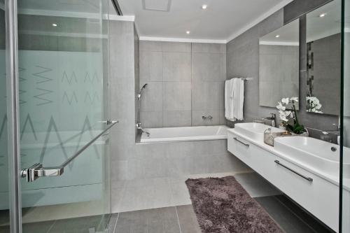 een badkamer met een bad, een wastafel en een douche bij SANDTON APARTMENT 15 WEST ROAD SOUTH in Johannesburg