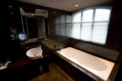 a bathroom with a tub and a sink and a mirror at Aston Hall Hotel, BW Signature Collection in Sheffield