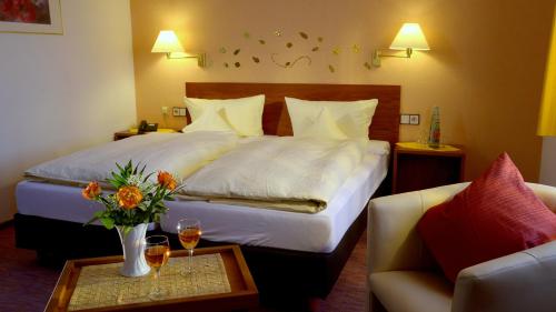 a hotel room with a bed and a table with wine glasses at Garni Hotel & Ferienwohnungen Seeschlößchen in Waldeck