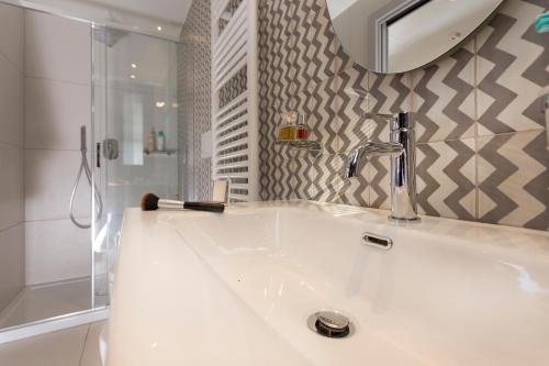 uma casa de banho com um lavatório, um espelho e um chuveiro em App Sea View em Riccione