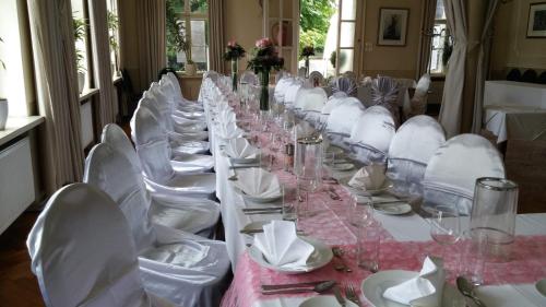 - une grande table avec des chaises blanches et des verres à vin dans l'établissement Gasthof Manhalter, à Pitten