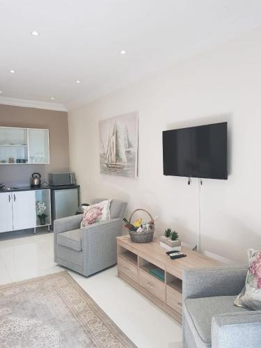 a living room with two chairs and a tv on the wall at Meraki Country Manor in Lanseria