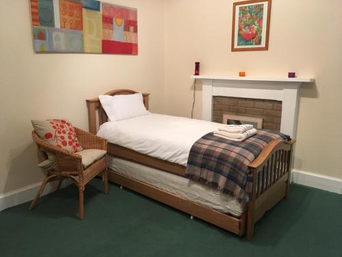 a bedroom with a bed and a chair and a fireplace at Netherwood House in Newtonmore