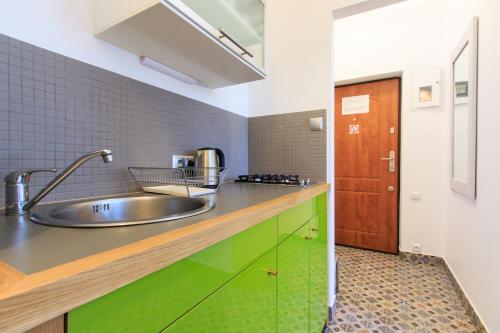 a kitchen with a stainless steel sink and green cabinets at Rental Apartments Bednarska in Warsaw