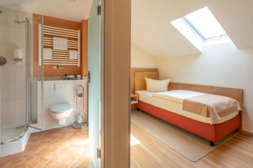 um quarto com uma cama e uma casa de banho com um chuveiro em Hotel Garni Brunnthaler em Garmisch-Partenkirchen