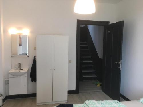 a bedroom with a staircase and a bathroom with a sink at Leonard room in Liège