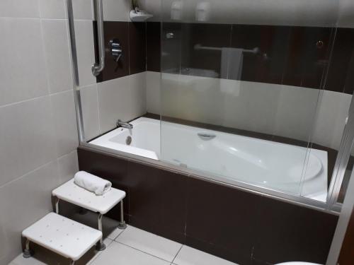 a bathroom with a tub and a toilet and a stool at Hotel Puerto Banana in El Guabo