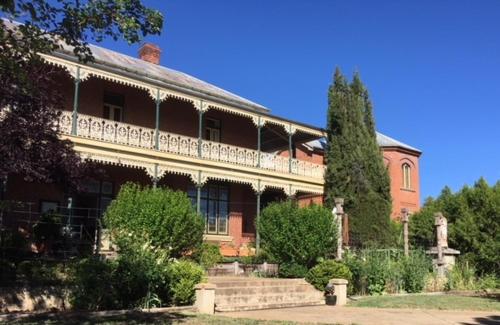 a large red brick building with a white balcony at Holmhurst Guest House in Bathurst