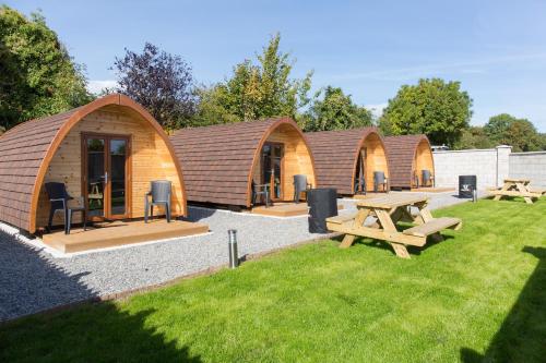 a row of wooden lodges with a picnic table and benches at Blackwater Eco Pods in Villierstown