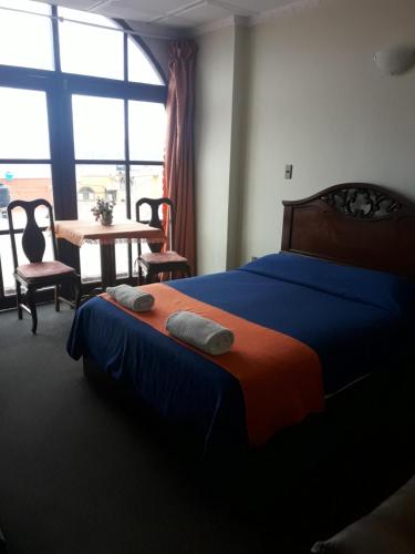 um quarto com uma cama, uma mesa e uma janela em Hostal Tukos La Casa Real em Potosí