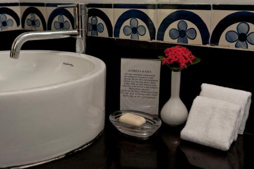 a bathroom counter with a sink and a vase of flowers at Presa di Goa - Managed by Smith and Appy in Calangute