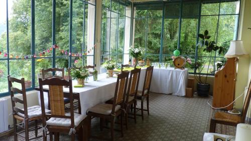 une salle à manger avec une table, des chaises et des fenêtres dans l'établissement Domaine de la Sauge, à Saint-Christophe