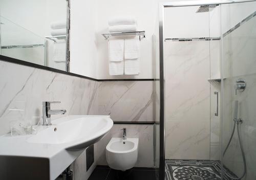 a white bathroom with a sink and a shower at Hotel Plaza in Turin
