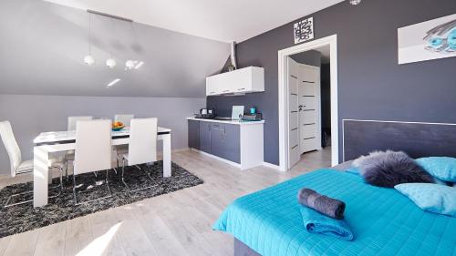 a bedroom with a blue bed and a table and a kitchen at Apartament Perła Pienin in Dębno