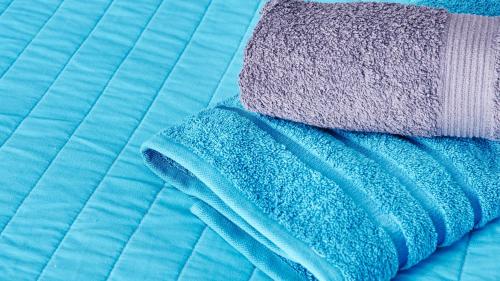a pile of blue and purple towels on a bed at Apartament Perła Pienin in Dębno