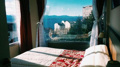 a bedroom with a window with a view of a city at BarilocheCentro I in San Carlos de Bariloche