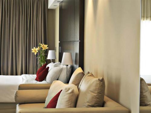 a hotel room with two beds and a couch with pillows at HTL City Baires in Buenos Aires