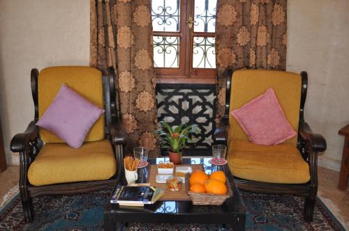 a living room with two chairs and a table with oranges at Teacook Marrakech in Ouled el guerne