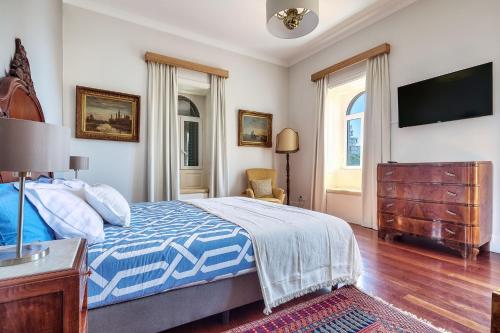 a bedroom with a bed and a dresser and a tv at Century House with private pool by HR Madeira in Funchal