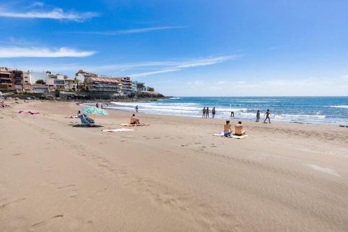 a group of people sitting on a beach at Apartamento a pie de playa in Melenara