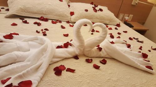 two white swans laying on a bed covered in roses at Manacá Apartamentos , Kariri Beach , Cumbuco in Cumbuco