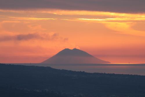 a mountain in the middle of the ocean at sunset at 501 Hotel in Vibo Valentia