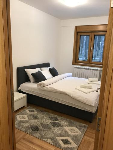 Un dormitorio con una cama con sábanas blancas y una ventana. en Zlatibor apartmani Jakovljevic, en Zlatibor