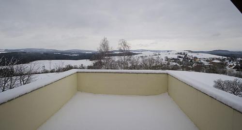 a snow covered balcony with a view of a snowy field at Panorama-Apartments Weinberghaus in Mittelndorf