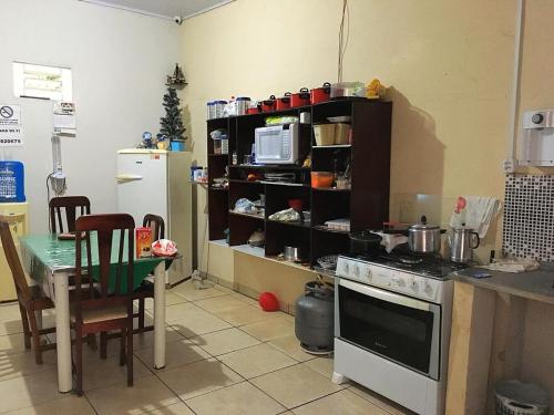 a kitchen with a stove and a table and a microwave at Pousada CPA in Cuiabá