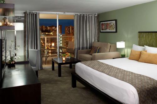 a hotel room with a bed and a living room at Skyline Island Colony Hotel in Honolulu