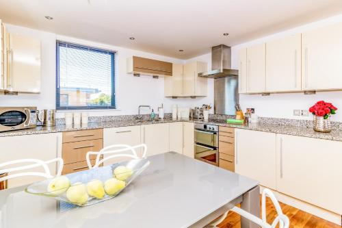 a kitchen with white cabinets and a table at Oxfordshire Living - The Monroe Apartment - Oxford in Oxford