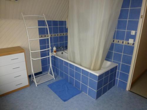 bagno piastrellato blu con vasca e tenda doccia. di Welcome a Guécélard