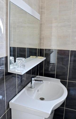 a bathroom with a white sink and a mirror at Meryem's Hotel in Kérynia