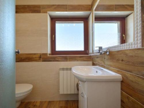 La salle de bains est pourvue d'un lavabo, de toilettes et d'une fenêtre. dans l'établissement Pokoje Gościnne Agusia, à Zakopane