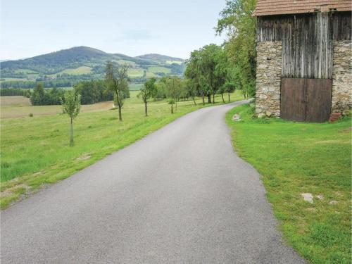a dirt road next to a barn and grass at Stylová chalupa na kraji národního parku Šumava in Strunkov