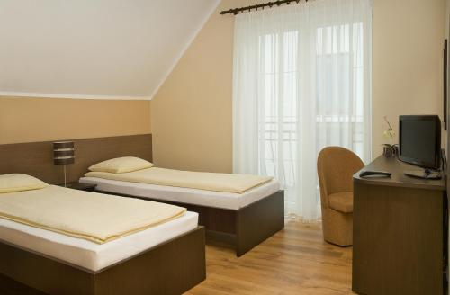 a hotel room with two beds and a television at Sand Residence - Pokoje i Apartamenty in Władysławowo