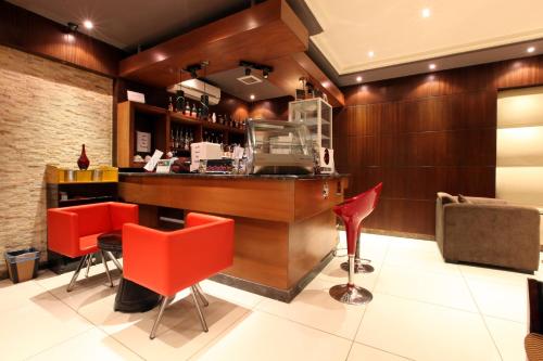 un bar en un restaurante con sillas rojas en Taleen AlSulaimanyah hotel apartments en Riad