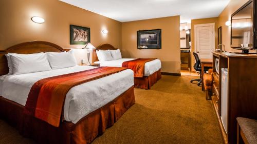 a hotel room with two beds and a desk at Best Western Sicamous Inn in Sicamous