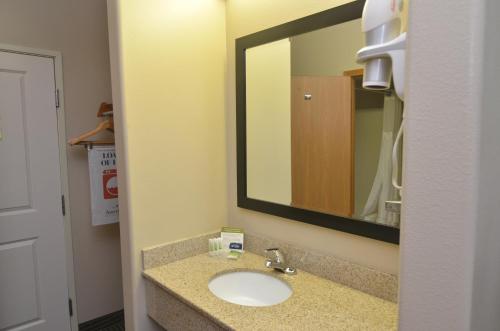 a bathroom with a sink and a large mirror at AmericInn by Wyndham Des Moines Airport in Des Moines