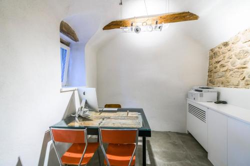 a kitchen with a glass table and orange chairs at Casa Kaki in Malcesine