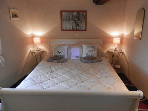 a bedroom with a large white bed with two lamps at La petite Cretouffiere - Naturiste Accommodation - Adult Only in Colombiers-du-Plessis