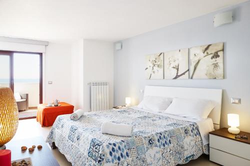 ein weißes Schlafzimmer mit einem Bett und einem Stuhl in der Unterkunft Aura CaseSicule, only for Sea View Lovers, Modern Style Apartment in City Center, Wi-Fi in Pozzallo